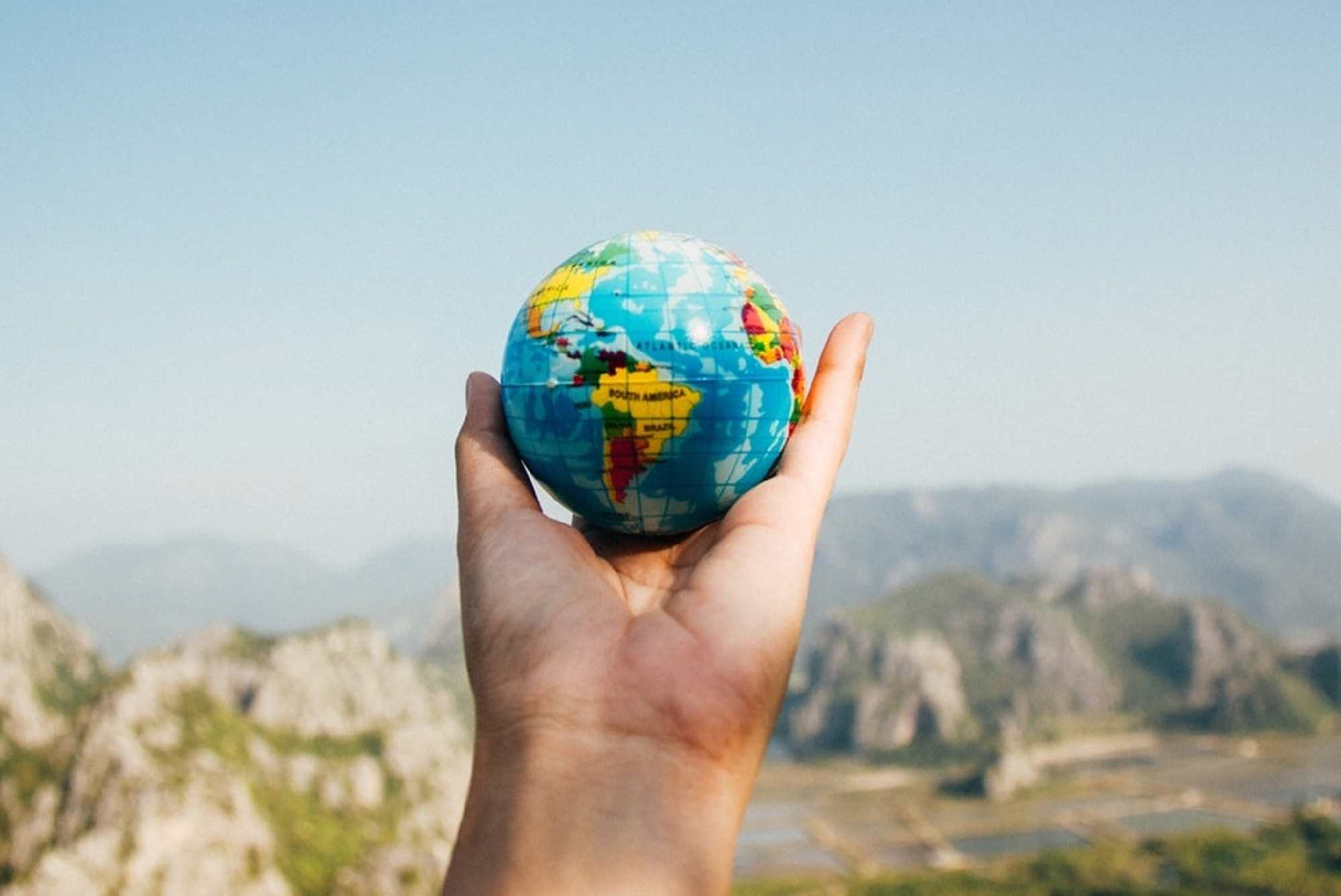 A hand holding a small globe